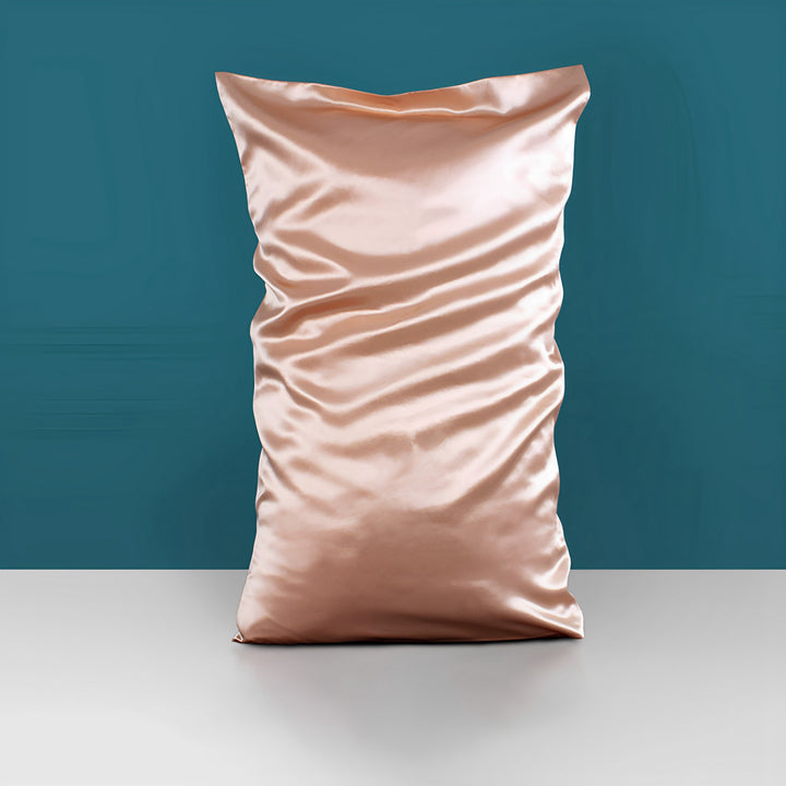 A 22 Momme High Gloss SusanSilk satin pillowcase in peach is displayed against a teal background on a white surface.