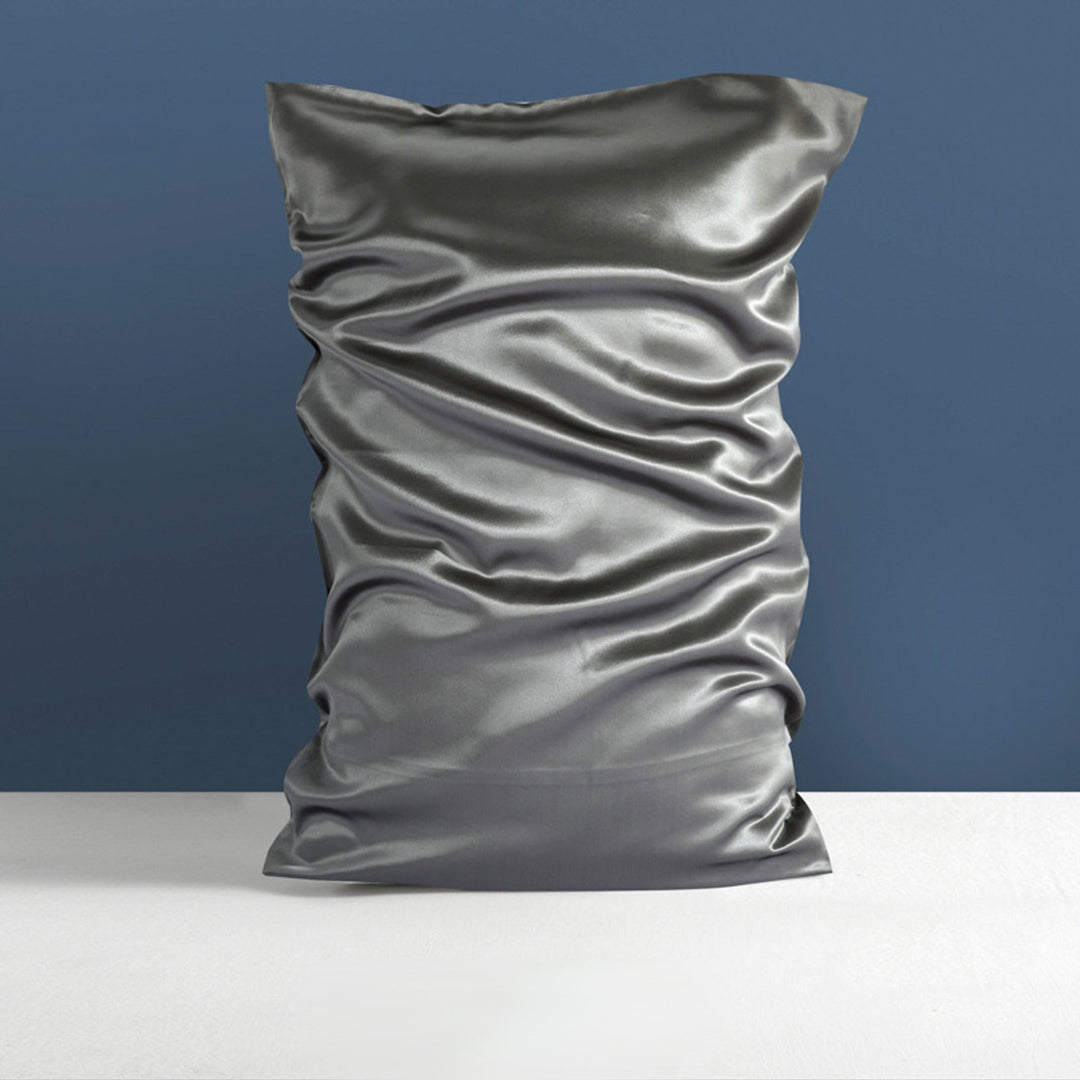 A neatly displayed SusanSilk 22 Momme High Gloss Silk Pillowcase Envelope in silver against a dark blue wall background.