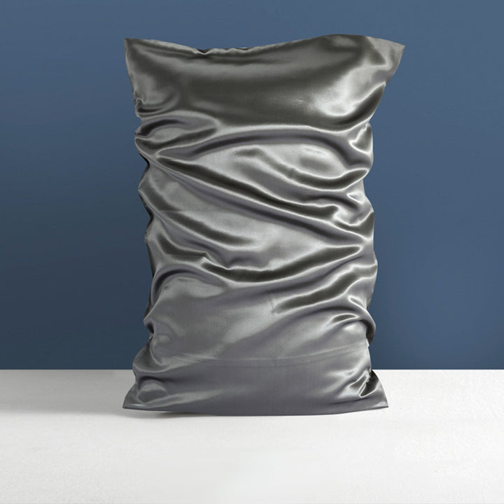 A neatly displayed SusanSilk 22 Momme High Gloss Silk Pillowcase Envelope in silver against a dark blue wall background.