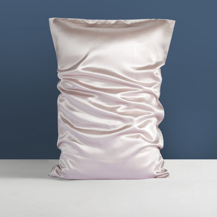 A soft, light-colored 22 Momme High Gloss Silk Pillowcase from SusanSilk with gentle wrinkles rests against a serene blue background atop a crisp white surface.