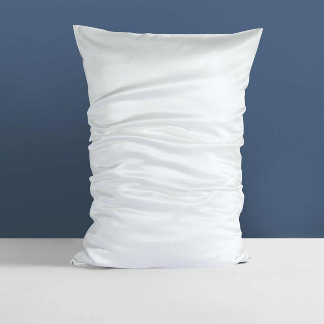 A 22 Momme High Gloss Silk Pillowcase Envelope by SusanSilk, featuring a pristine white hue and noticeable creases, sits elegantly against a blue wall on a flat surface.