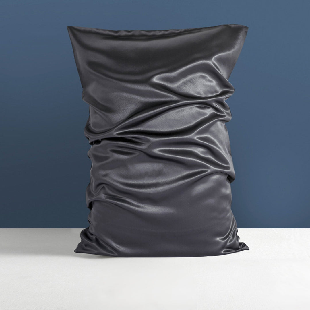 A black 22 Momme High Gloss Silk Pillowcase Envelope by SusanSilk rests on a white surface against a blue background.