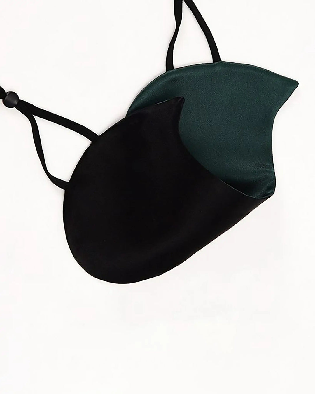 A black and green Cat Shape Silk Eye Mask from SusanSilk with adjustable straps lies on a white surface.