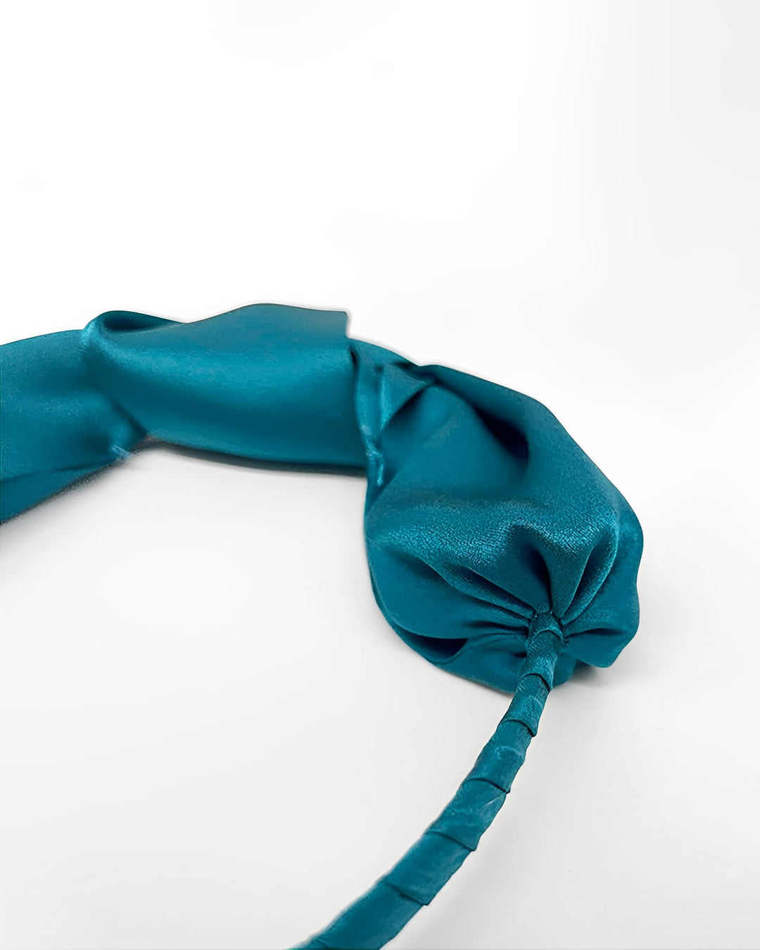 A teal "Pure Color Bow Knot Silk Headband" by SusanSilk lies on a white surface.