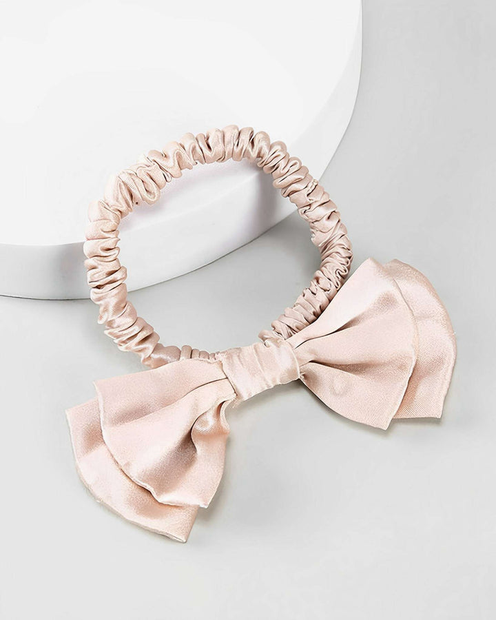 A luxurious Vintage Bow-Knot Silk Scrunchie by SusanSilk, featuring a large bow detail in beige satin, placed on a light grey surface.