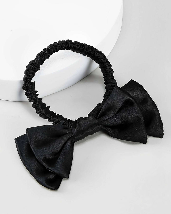 The SusanSilk Vintage Bow-Knot Silk Scrunchie is a black elastic hair tie adorned with a luxurious silk bow on a white background, perfect for adding a touch of elegance to any hairstyle.