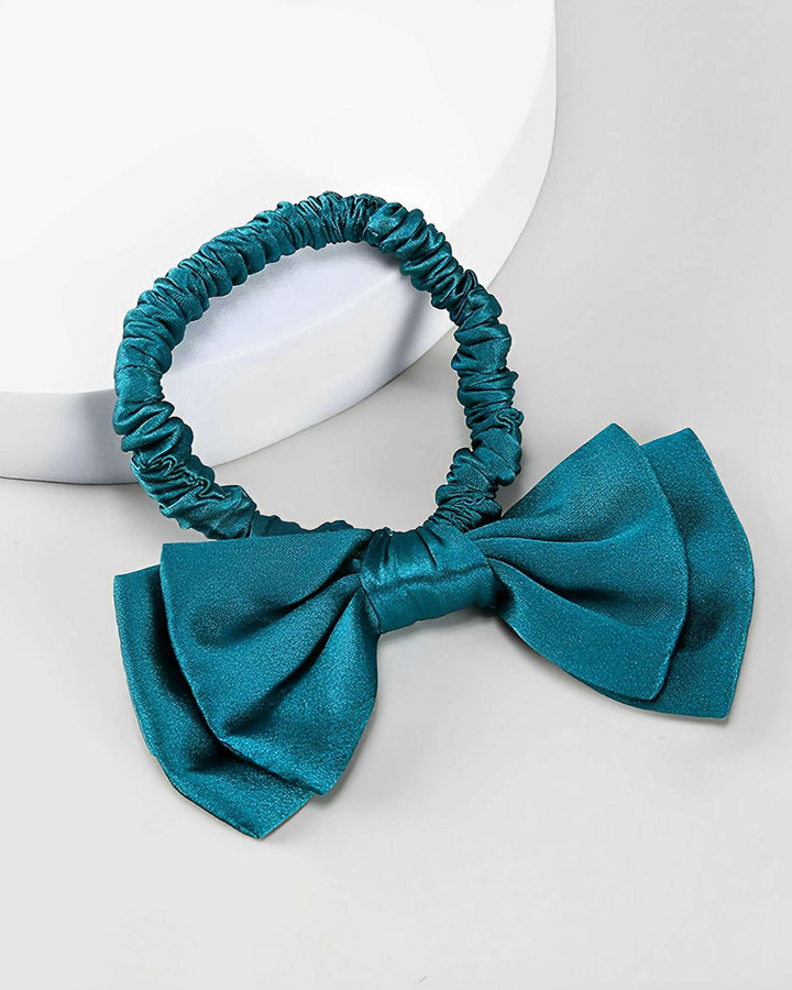 A SusanSilk Vintage Bow-Knot Silk Scrunchie in teal, featuring a large matching bow, placed on a white surface.
