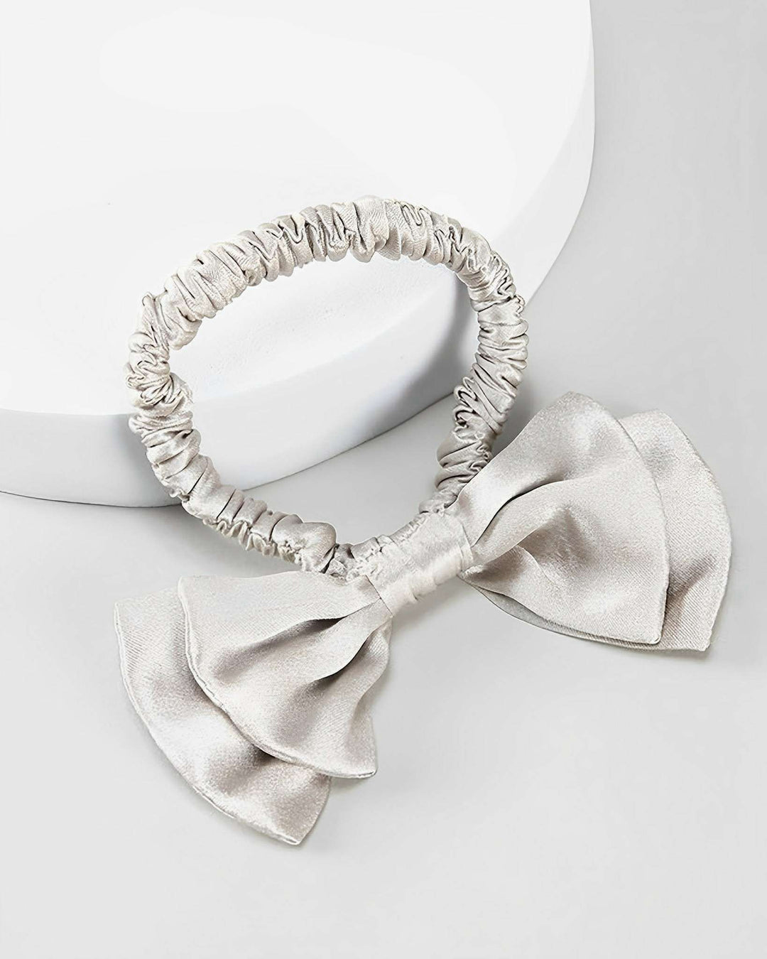 A Vintage Bow-Knot Silk Scrunchie, crafted from luxurious SusanSilk material with an attached bow, placed on a white and grey background.