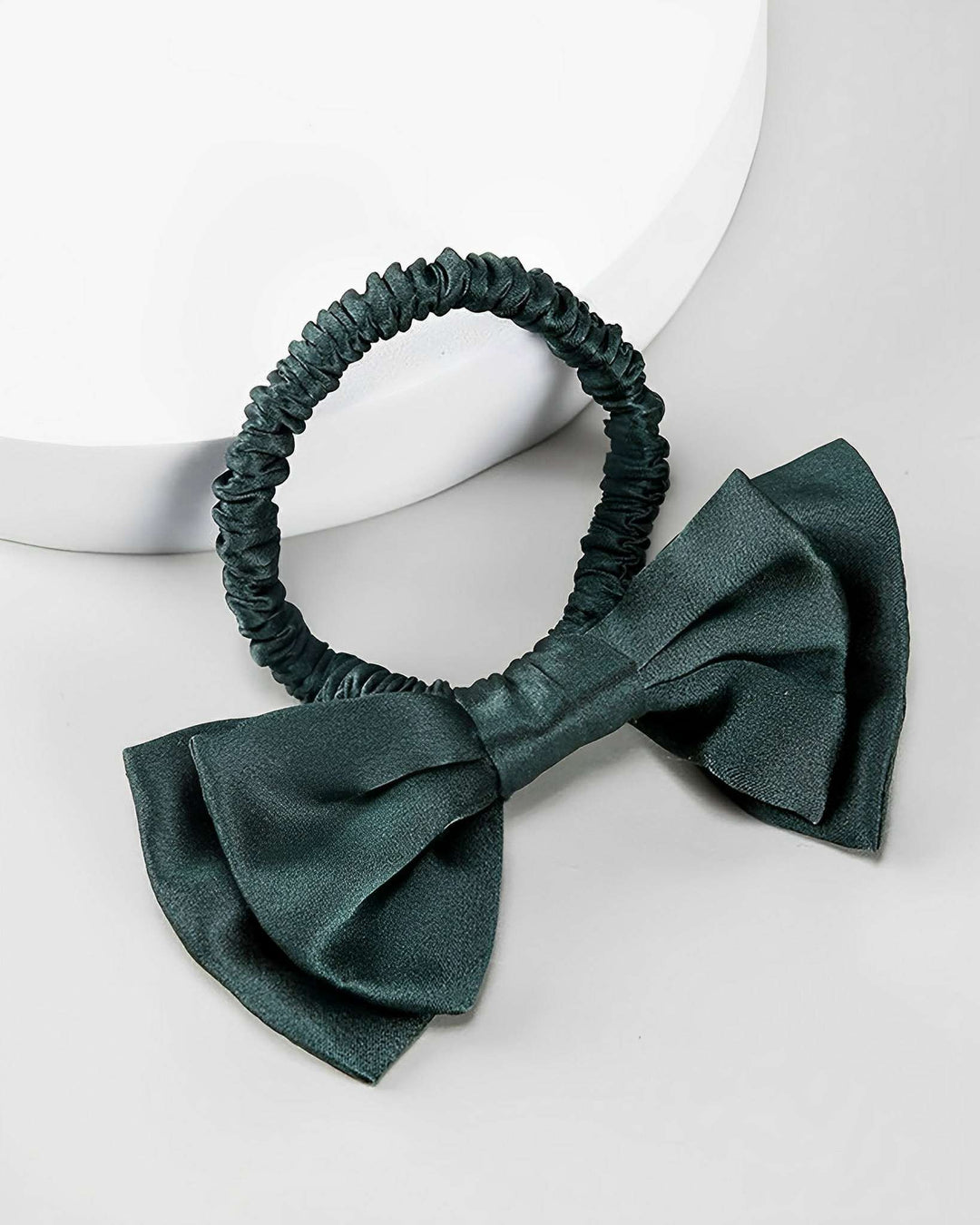 The **SusanSilk Vintage Bow-Knot Silk Scrunchie** in a dark green shade, featuring a large, matching bow, is displayed on a light-colored background.