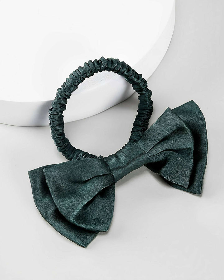 The **SusanSilk Vintage Bow-Knot Silk Scrunchie** in a dark green shade, featuring a large, matching bow, is displayed on a light-colored background.