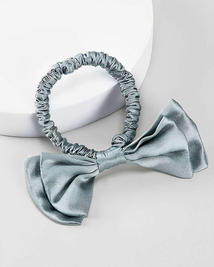 A light gray Vintage Bow-Knot Silk Scrunchie from SusanSilk featuring a large bow attachment on a white background.