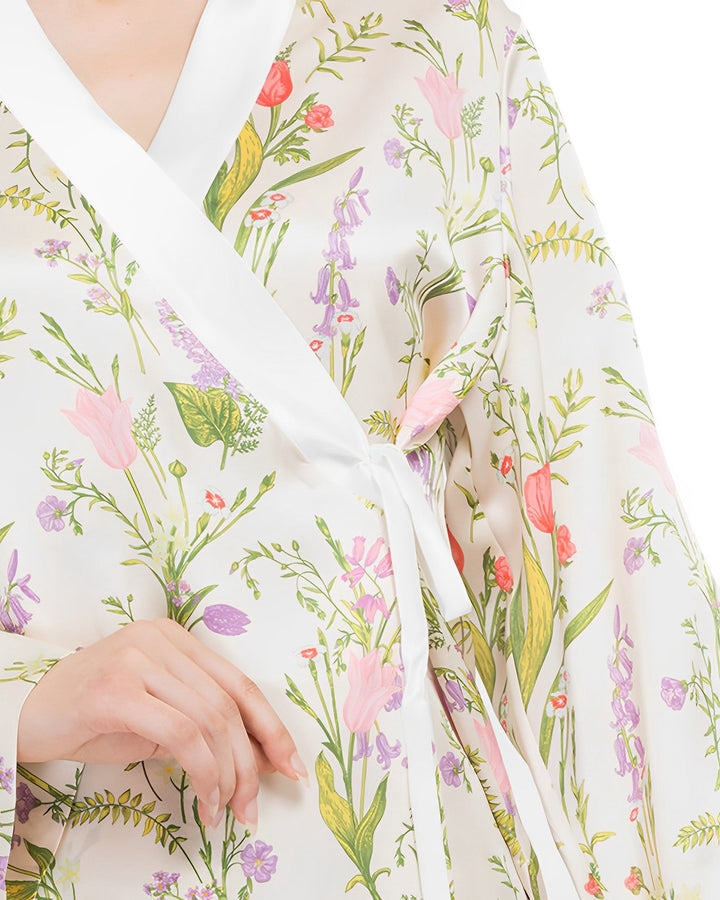 A person in the 19 Momme Floral Silk Wrap Pajamas Set by SusanSilk adjusts the tie near their waist, showcasing the luxurious fabric.