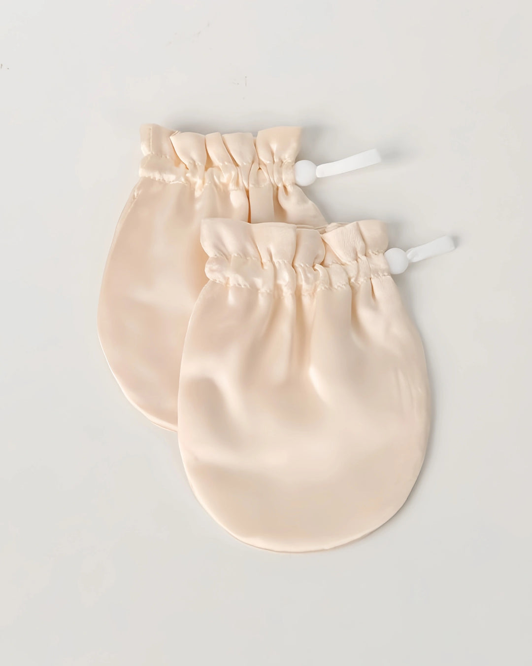 Close-up of ivory 19 momme baby silk gloves highlighting smooth mulberry silk texture that protects baby skin from irritation and scratching.