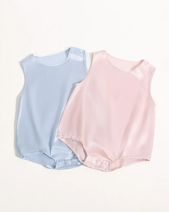 Three 19 Momme Silk Baby Button Onesies from SusanSilk in pastel colors (white, pink, and cream) are arranged side by side on a plain background. Each onesie features snap buttons on the shoulders and elastic leg openings, showcasing the gentle touch of SusanSilk for your baby's comfort1.