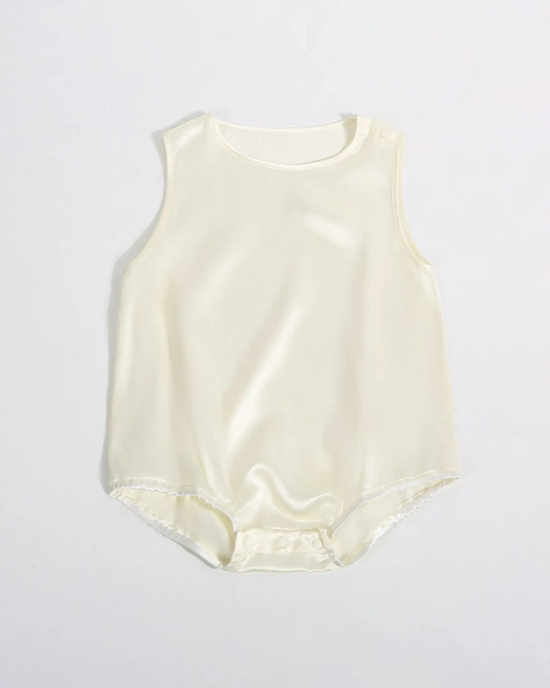 A sleeveless 19 Momme Silk Baby Button Onesie from SusanSilk, displayed flat on a gray background, with a sleek white design featuring snaps at the bottom for easy fastening