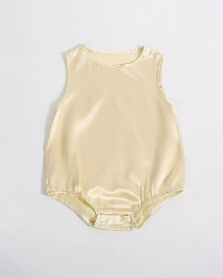 The 19 Momme Silk Baby Button Onesie by SusanSilk is a sleeveless, light beige baby romper made from soft silk, featuring a round neckline, shoulder snap buttons, and bottom snap closures