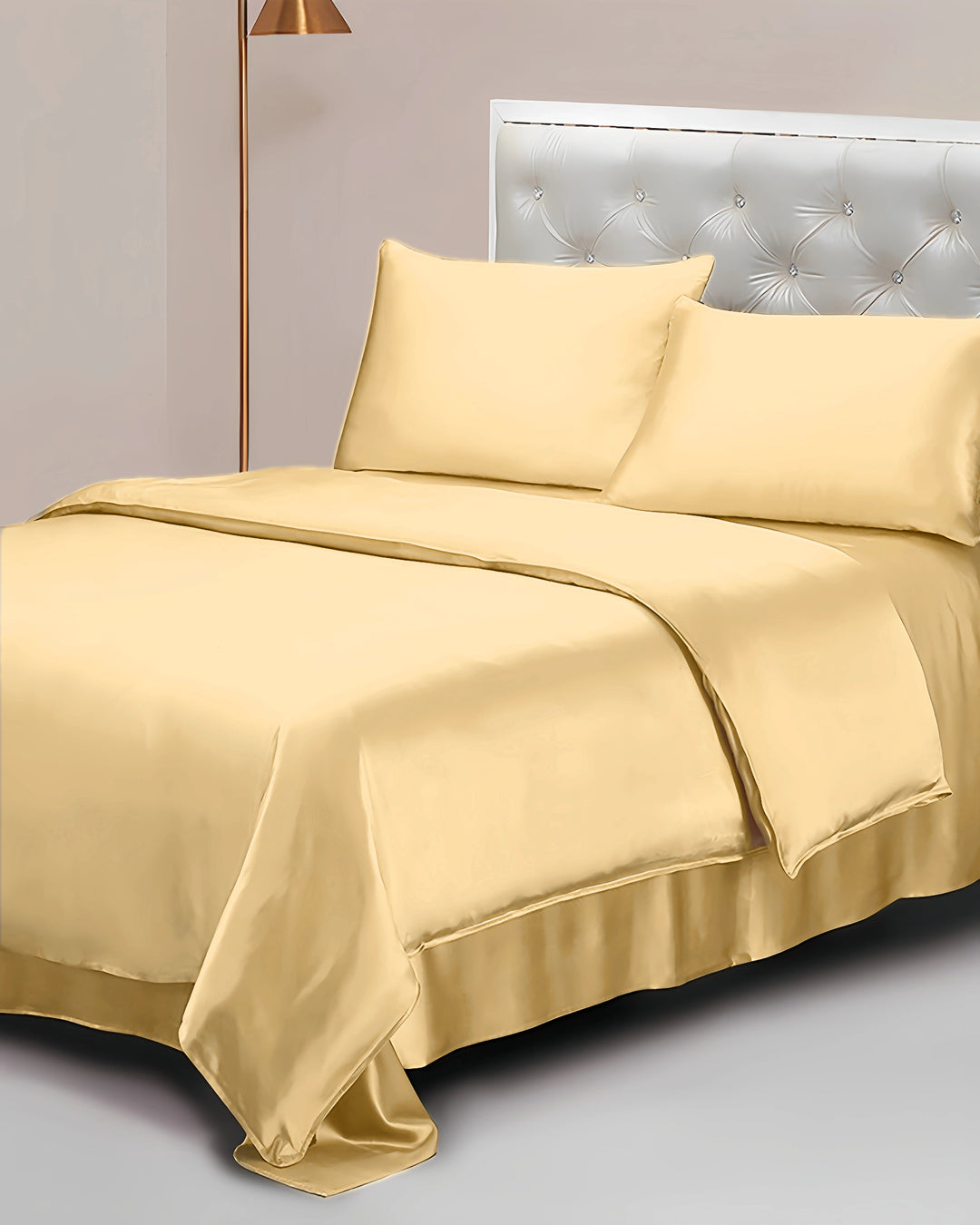 Gold satin bedding set on a bed with a neutral headboard.