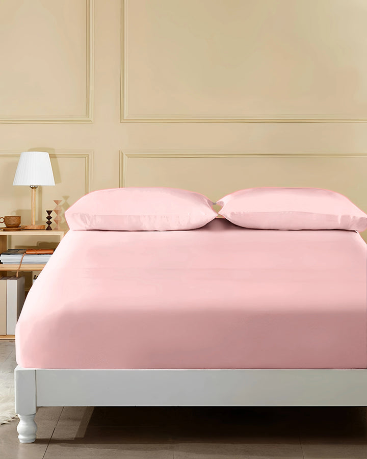 Pink bedspread on a neatly made bed in a bedroom setting.