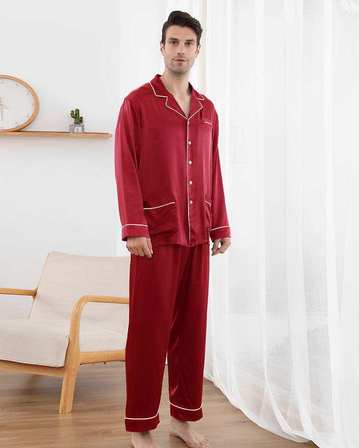 Man wearing red pajamas standing in a room with a white curtain and wooden chair.