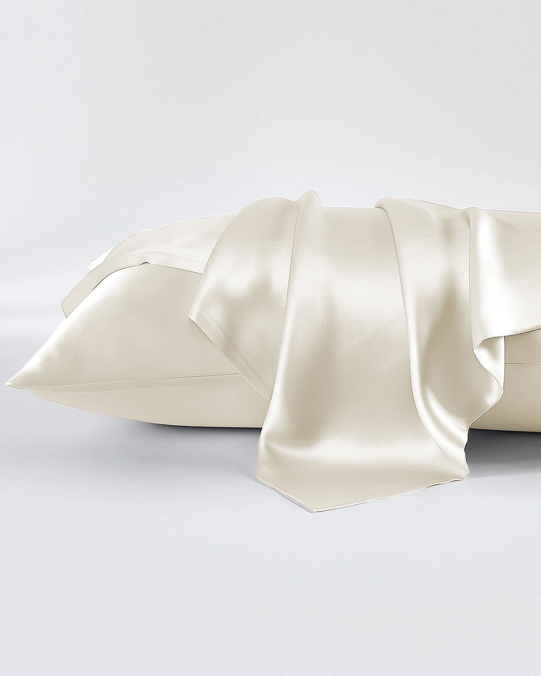 Cream-colored satin pillowcases on a light gray background