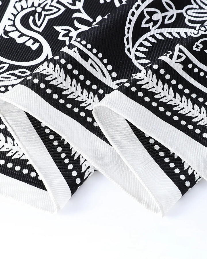 Close-up of a black bandana with white paisley patterns on a white background