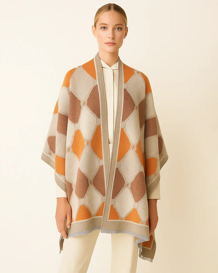 Woman wearing a patterned orange, beige, and white poncho against a plain background