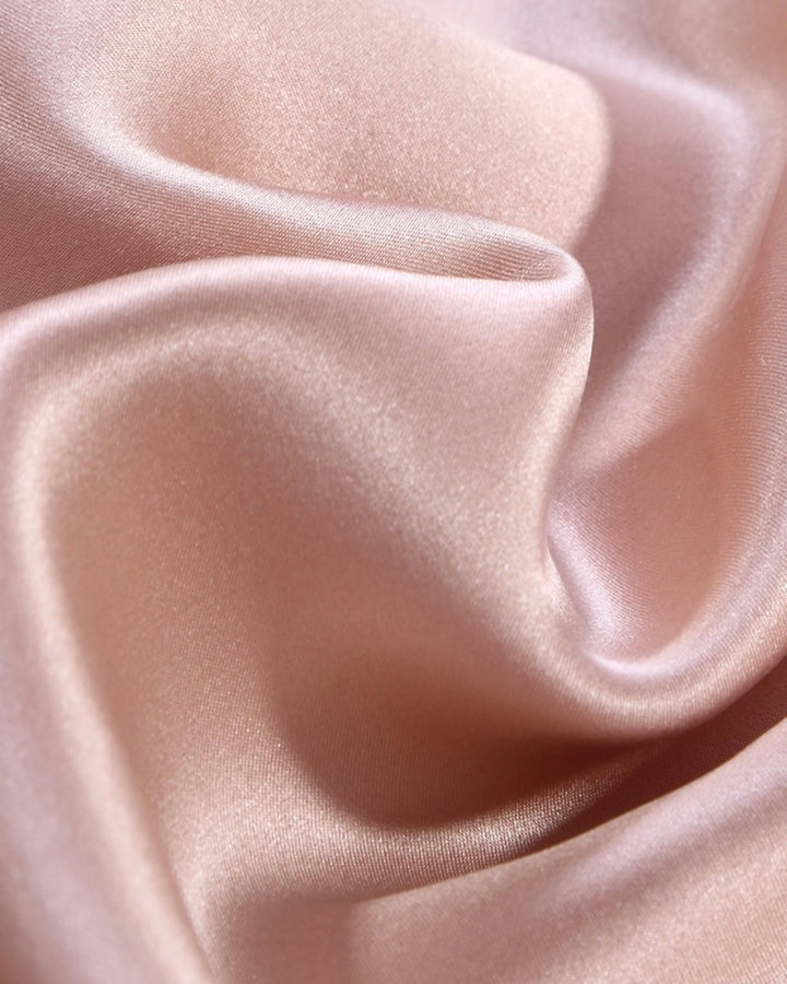 Close-up of smooth, light pink fabric with soft folds.
