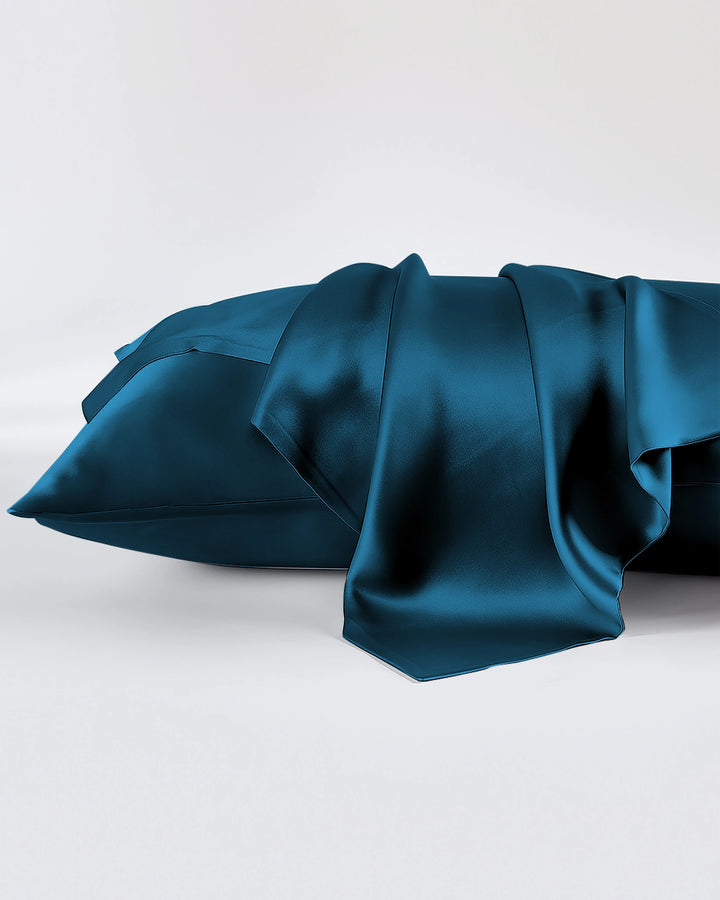 Teal satin pillowcases on a white background