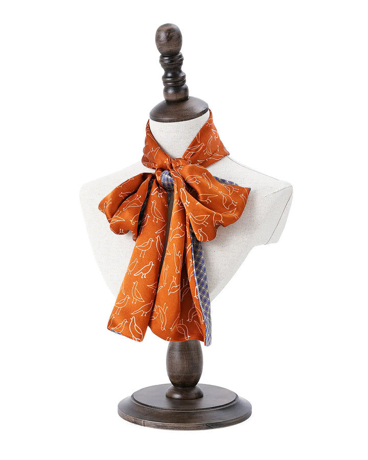 Mannequin torso with an orange patterned scarf on a white background