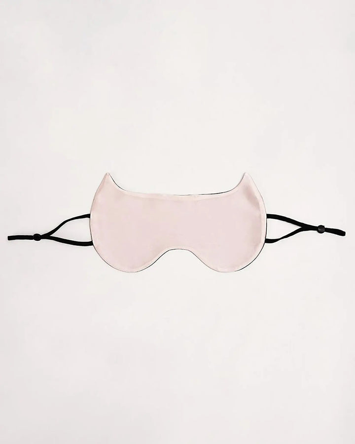 The Cat Shape Silk Eye Mask by SusanSilk, featuring pale pink silk material and black adjustable straps, is laid flat against a white background.