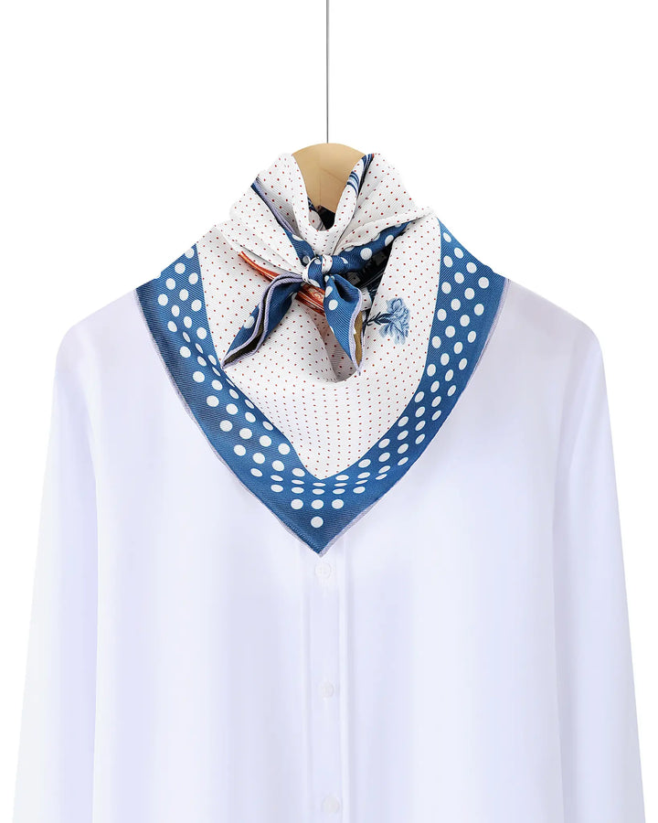 White blouse with a blue polka dot scarf draped over a mannequin on a white background