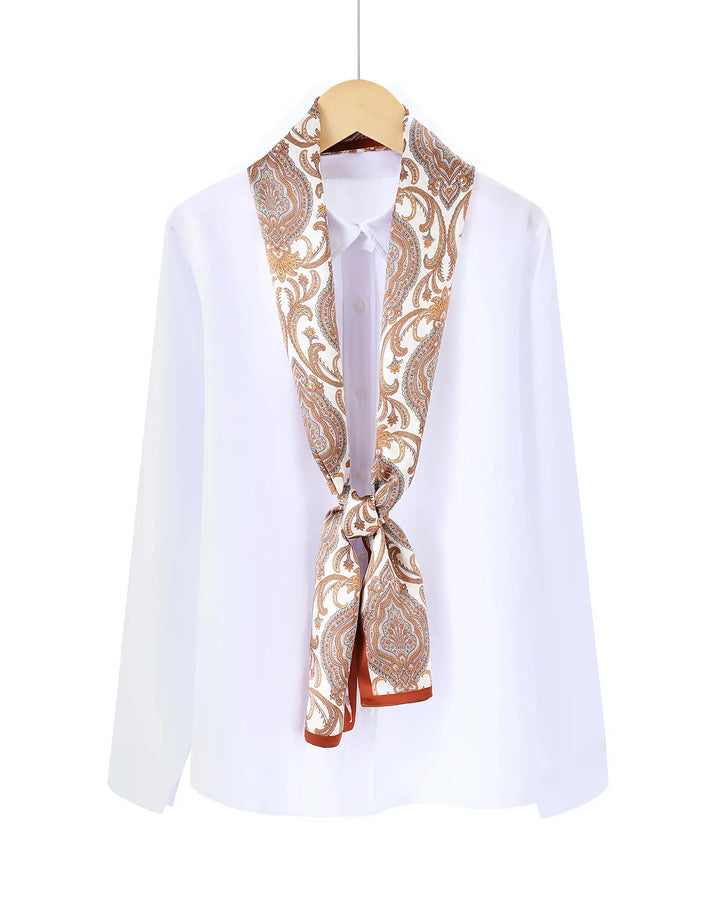 White shirt with a patterned scarf tied around the neck on a wooden hanger against a white background