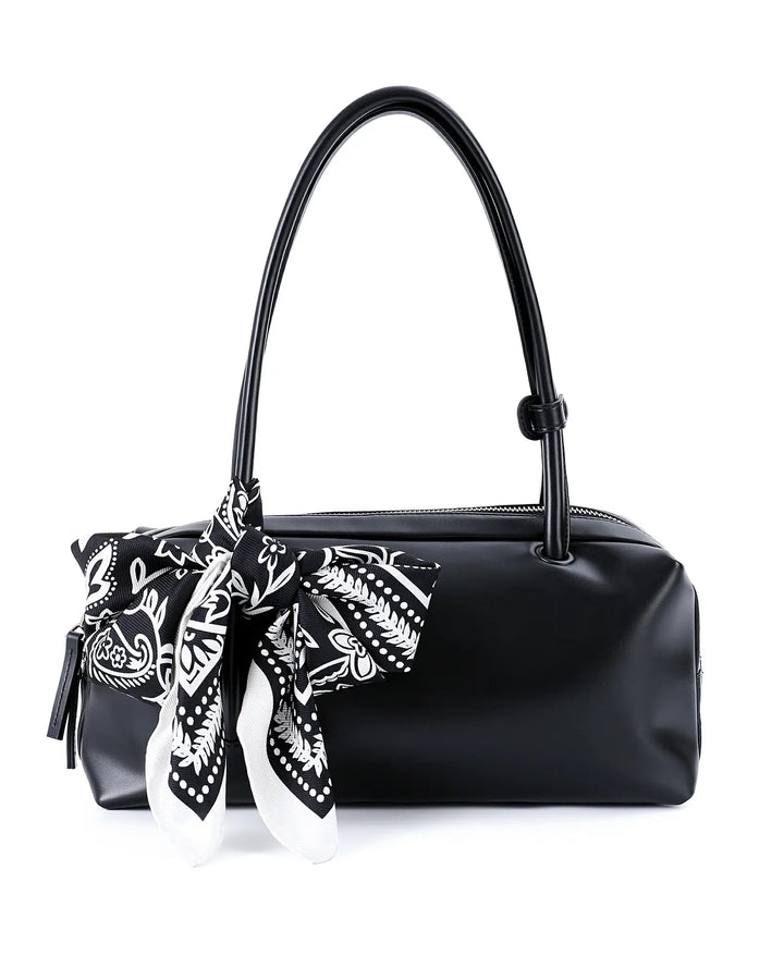 Black handbag with a black and white patterned scarf tied around it on a white background