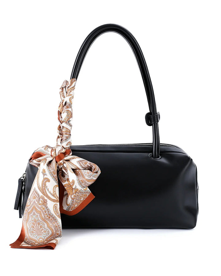 Black handbag with a patterned scarf draped over the handle on a white background