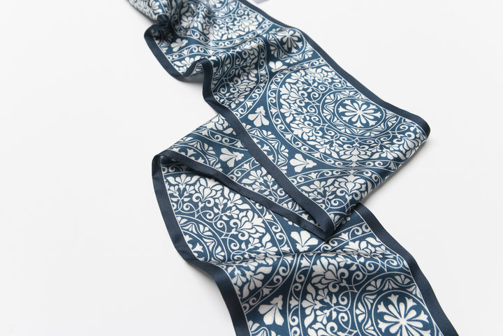 A Blue And White Silk Long Fluttering Belt by SusanSilk, adorned with intricate floral and geometric designs, laid out flat against a white background.