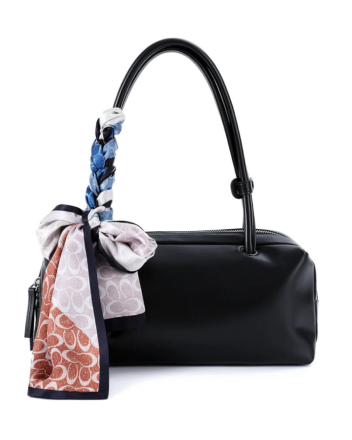 Black handbag with a colorful scarf tied around the handle on a white background