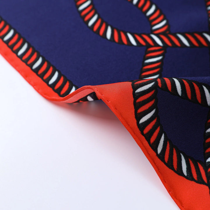 Close-up of the Witch Hazel Orange Square Silk Scarf by SusanSilk, featuring a navy blue base with a red and white rope pattern and a red edge.