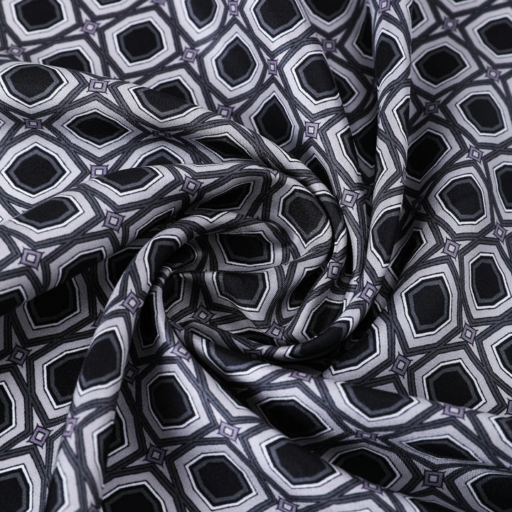 Close-up of the Sakuma Gray Square Silk Scarf by SusanSilk, featuring a geometric pattern of interconnected hexagons in shades of black, gray, and white, showing a twisted fold in the center.