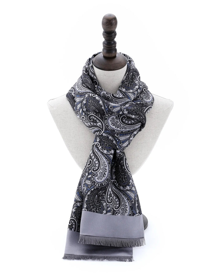 A gray and black paisley patterned scarf with a solid gray fringed border, displayed on a white mannequin bust against a white background.#color_silver