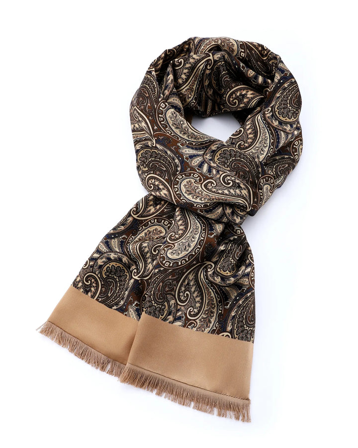 A paisley pattern scarf in brown, beige, and black, featuring a solid tan border and fringed ends, displayed on a clean white background.#color_antique-gold