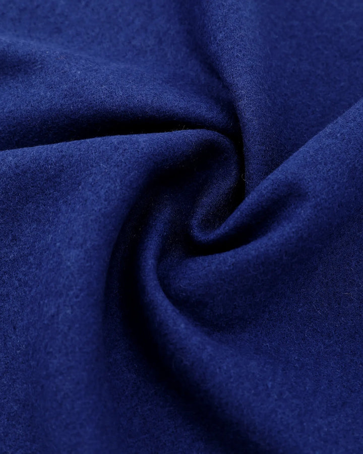 A close-up of deep blue fabric with a soft, slightly fuzzy texture, arranged in a spiral drape pattern.#color_navy-blue