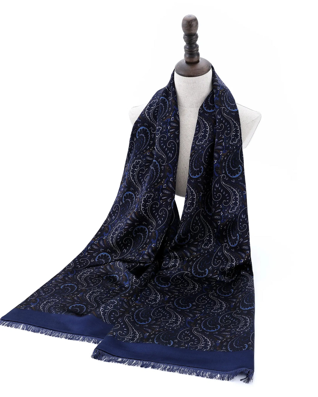 A navy blue scarf with a detailed paisley pattern and fringed edges, draped on a white dress form mannequin against a plain white background.#color_navy-blue