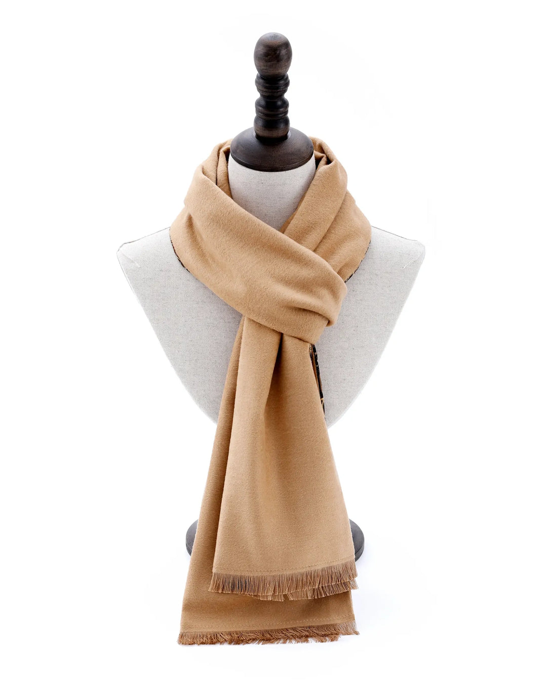 A light tan woven scarf with fringed edges, draped around a light gray fabric mannequin bust with a dark wooden neck cap, set against a plain white background.#color_antique-gold