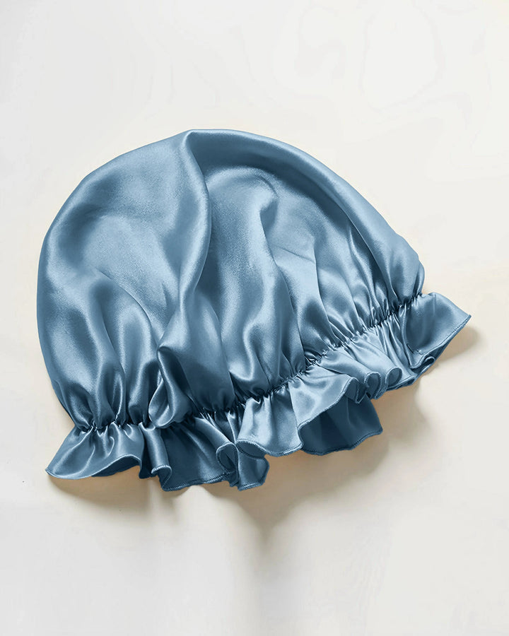Blush pink mulberry silk ruffled sleep bonnet laid flat, soft silk bonnet with feminine ruffled elastic edge