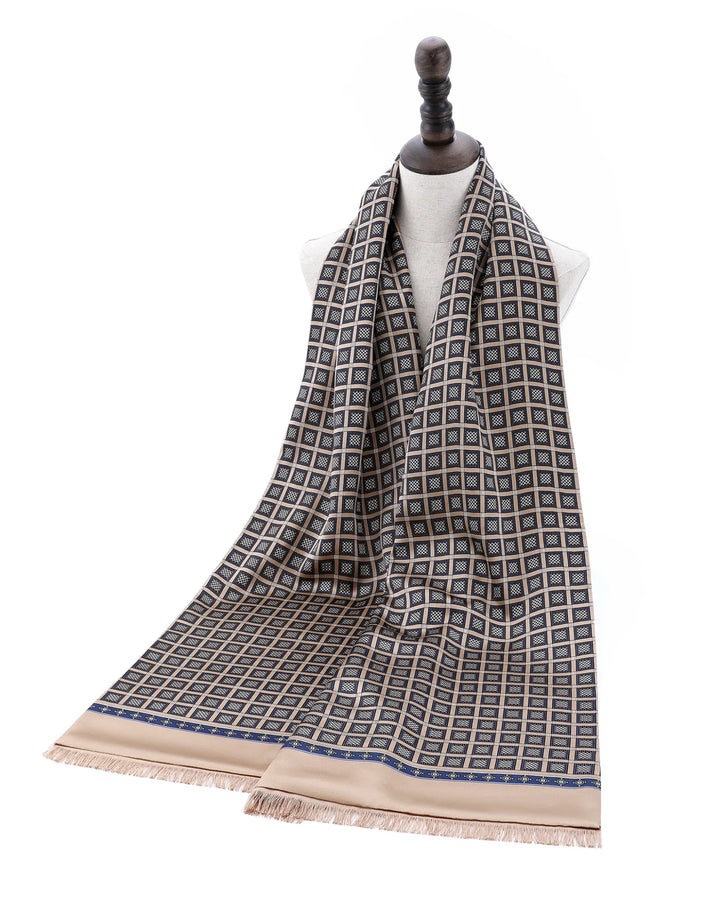 A patterned scarf draped on a white mannequin torso, featuring a geometric grid design in beige, gray, and blue with fringed ends.#color_antique-gold