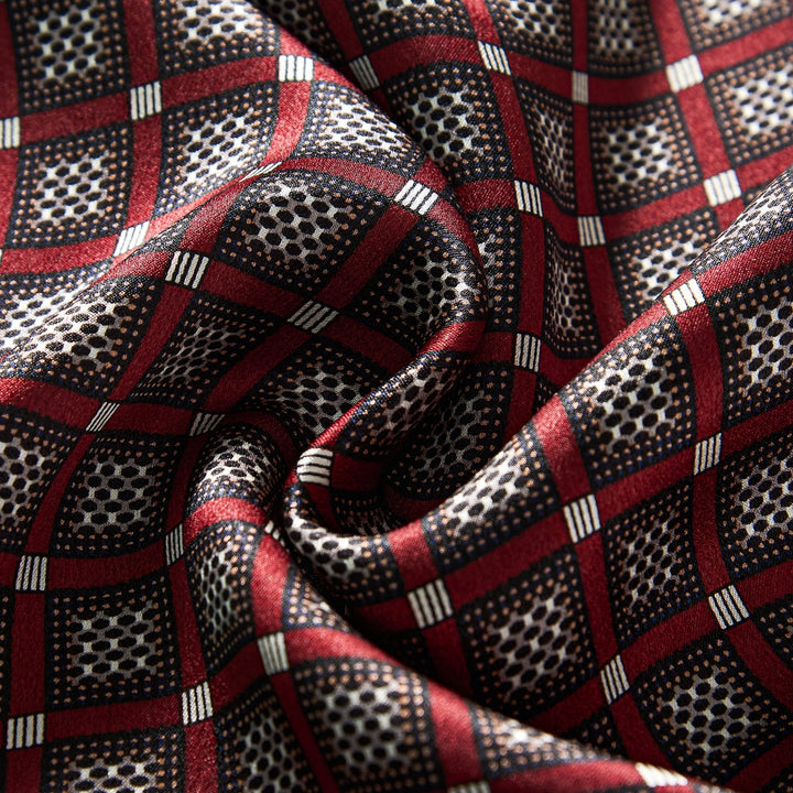 Close-up of the Journey Grid Series Long Silk Scarf by SusanSilk, showcasing a red and black checkered pattern with small white dots inside black squares and red borders. The silk material appears to be soft and slightly wrinkled.