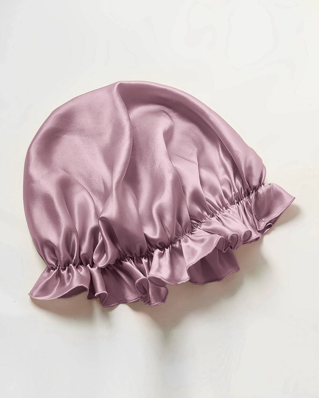 Dusty rose mulberry silk ruffled sleep bonnet laid flat, elegant elastic edge design made from pure mulberry silk
