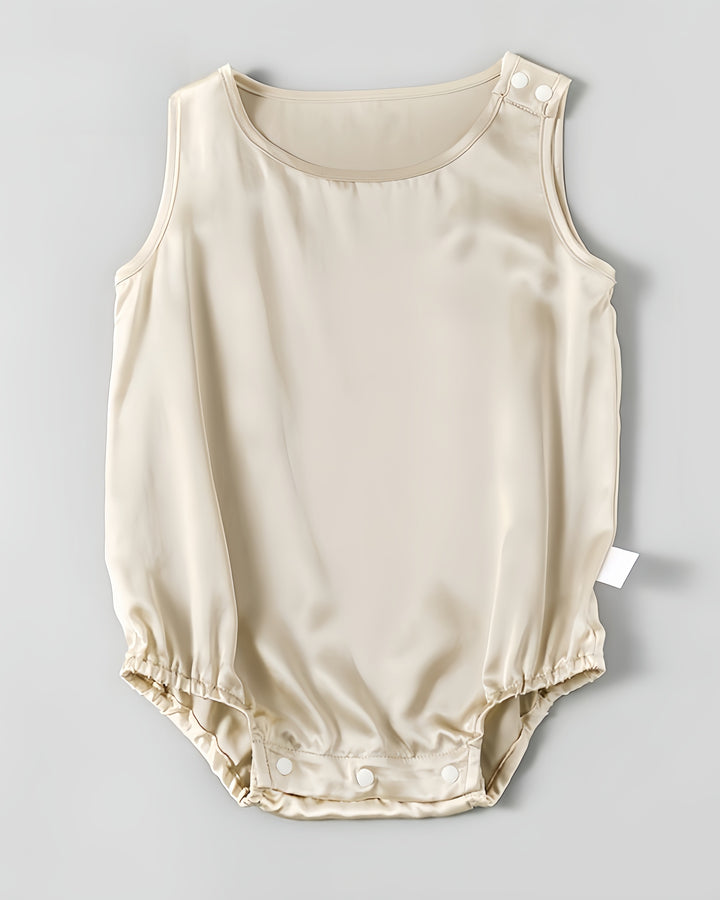 The 19 Momme Silk Baby Button Onesie by SusanSilk is a sleeveless, light beige baby romper made from soft silk, featuring a round neckline, shoulder snap buttons, and bottom snap closures.