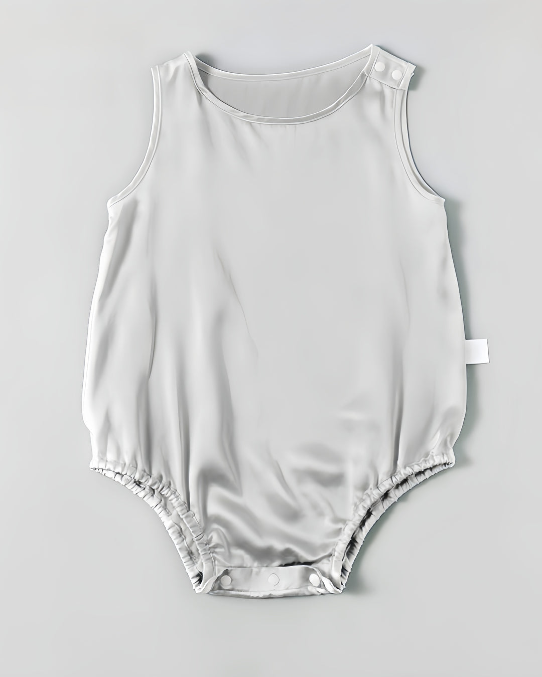 The 19 Momme Silk Baby Button Onesie by SusanSilk is a light gray, sleeveless romper featuring snap buttons on the shoulder and at the bottom, crafted from a luxurious silk blend for added comfort.
