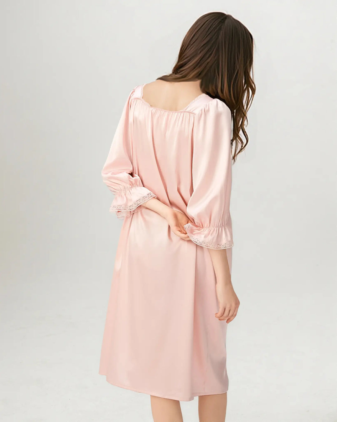 Woman wearing a pink satin nightgown on a white background.#color_rose-pink